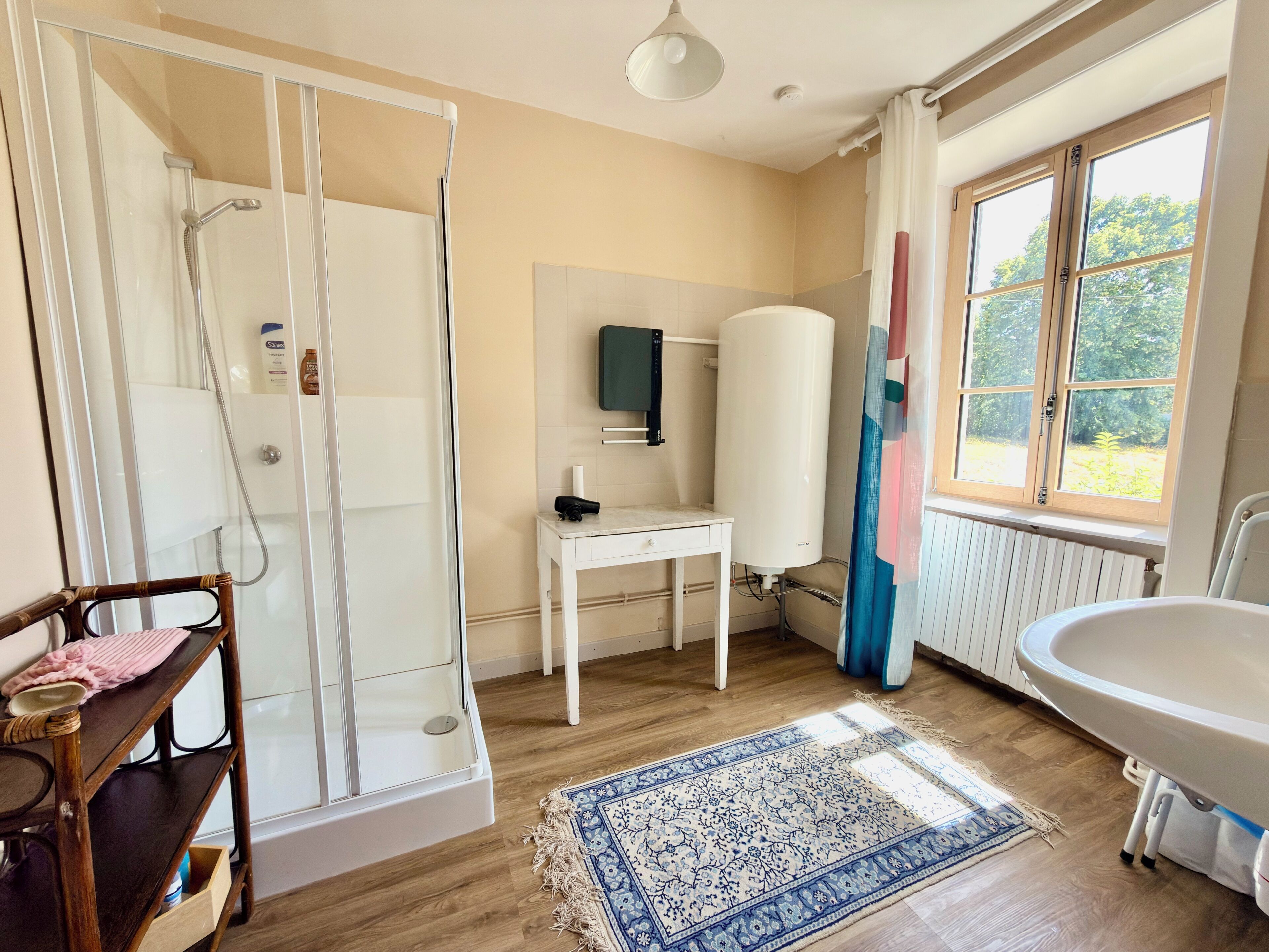 Ein Badezimmer mit Dusche, Toilette, Waschbecken, Spiegel und Fenster.
