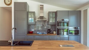 Une cuisine moderne avec des meubles gris, une hotte en acier inoxydable et un four double.