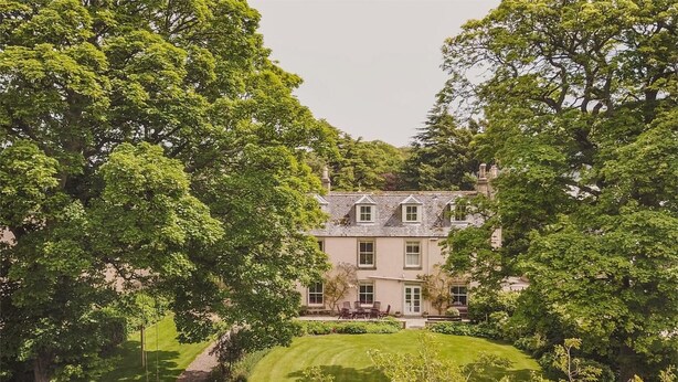 A large, multi-story building surrounded by lush greenery and a well-maintained lawn. - 6 Bed in Fochabers (oc-ca102) (Fochabers)