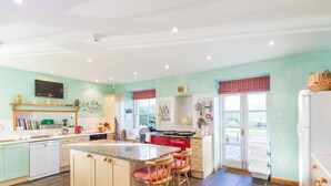 A kitchen with a central island, bar stools, a built-in oven, and a refrigerator. - 6 Bed in Fochabers (oc-ca102) (Fochabers)