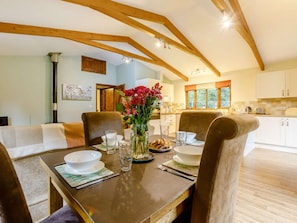 A dining area with a wooden table, chairs, and a vase of flowers.