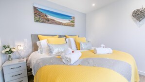 Une chambre d’hôtel bien rangée, avec un lit, des tables de chevet, un tableau et un élément décoratif mural.