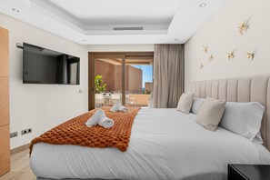 Ett modernt hotellrum med en stor säng, en platt-TV, en balkong med utsikt och en matplats.