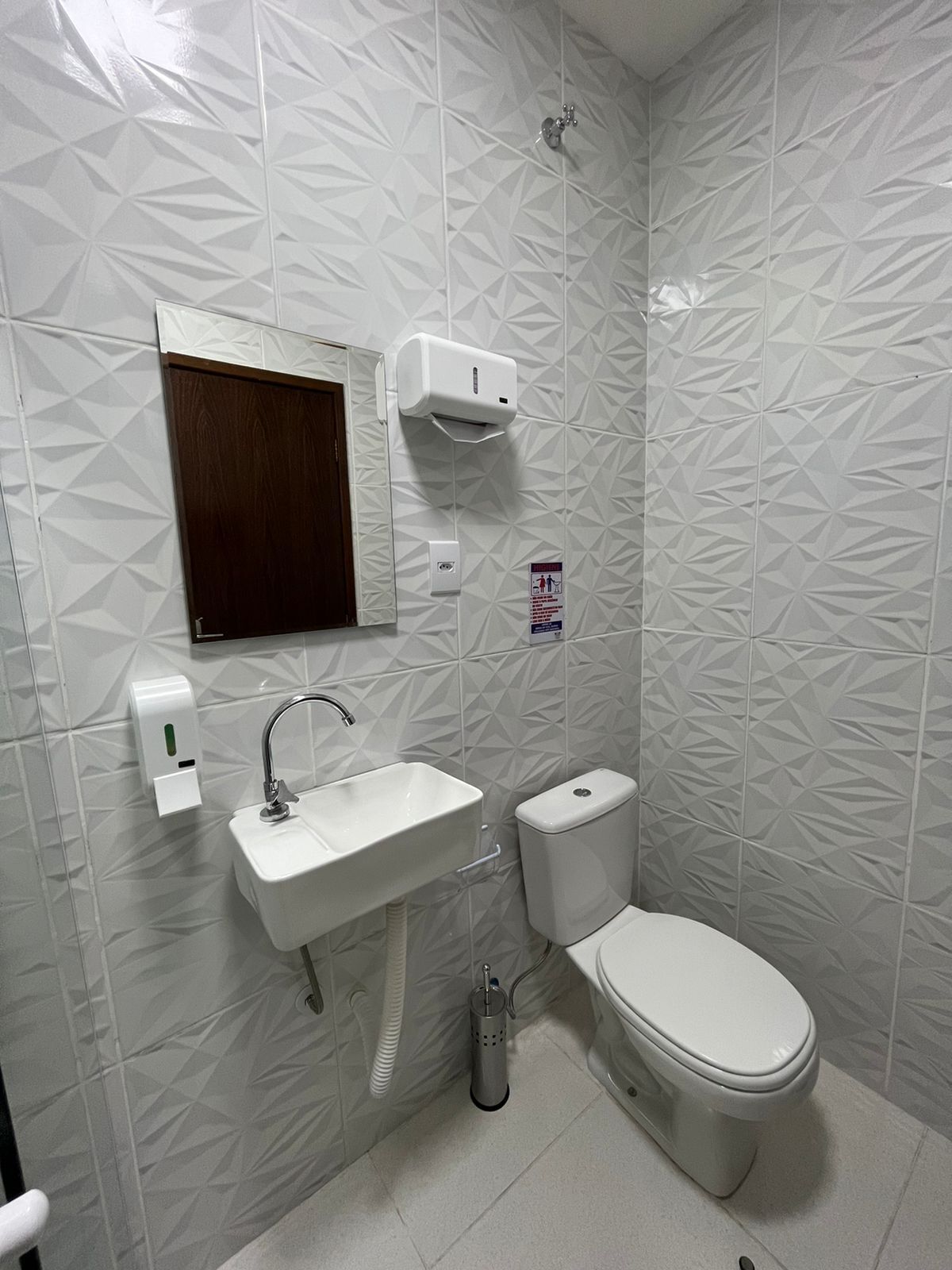 A bathroom with a white sink, toilet, and a hand dryer.