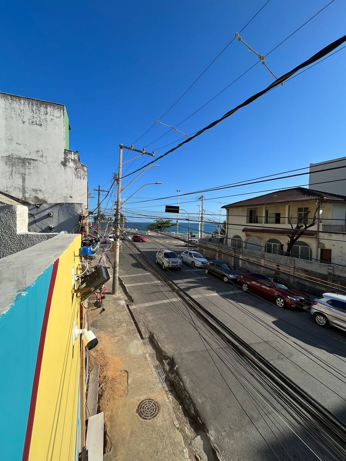 A street with cars, overhead power lines, and buildings.