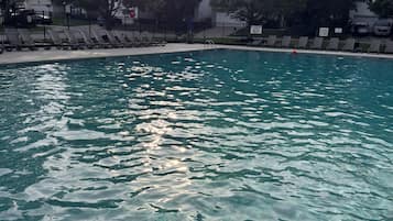 Une piscine aux eaux cristallines, avec un ciel ensoleillé et des arbres en arrière-plan.