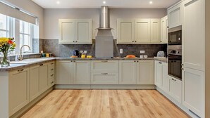 Une cuisine moderne avec des meubles de couleur claire, une hotte en acier inoxydable et un plancher en bois.