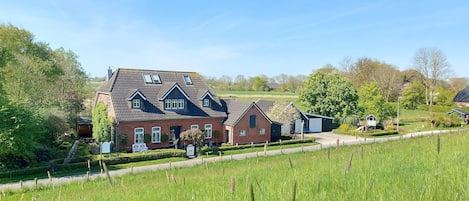A large house with a sloped roof, a small shed, and a well-maintained lawn.