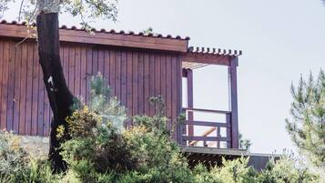 Ein Holzhaus mit Balkon, umgeben von üppiger Vegetation.