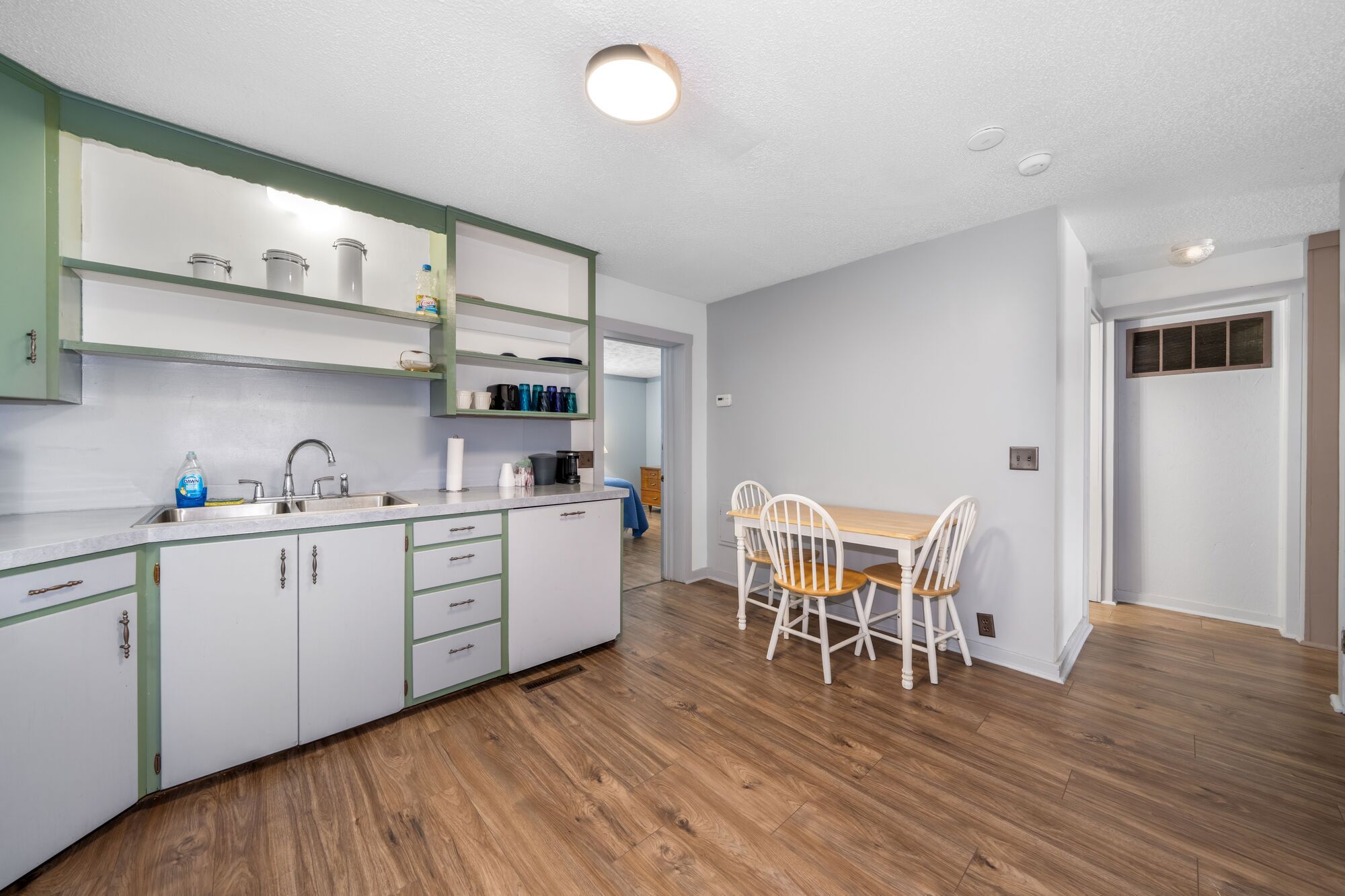 A modern kitchen with white cabinets, a wooden dining table, and chairs.
