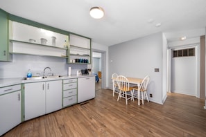 A modern kitchen with white cabinets, a wooden dining table, and chairs. - Apartment in Beautiful Auburn Ne (Auburn)