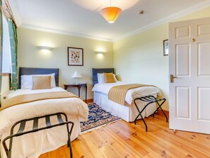 Habitación de hotel con dos camas, una mesita, una silla, un tapete y una puerta.