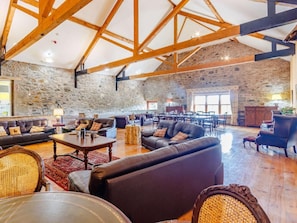 A spacious room with stone walls, wooden beams, leather sofas, and a dining area with tables and chairs. - 8 Bed in Kirriemuir (oc-ca261) (Kirriemuir)