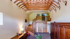 Ein geräumiger Korridor mit Holzbalken, einer Treppe und einem Empfangstresen mit Lampe.