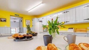 Eine Küche mit gelben Wänden, weißen Schränken und einer Frühstücksvorplatte mit Croissants und Muffins.
