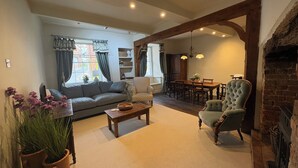 Una sala de estar con sofá, sillón, mesa de centro y chimenea.