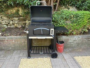 A portable grill with a lid, a handle, and a wheel for mobility.