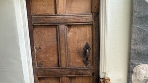 Una puerta de madera con un picaporte de metal, barandilla de madera y pared con textura.
