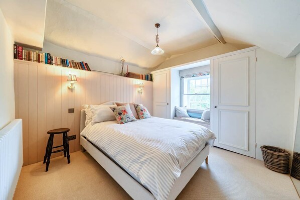 A bedroom with a bed, a window seat, a bookshelf, and a radiator. - Characterful Townhouse | Central 3 Bed + Parking (Ludlow)