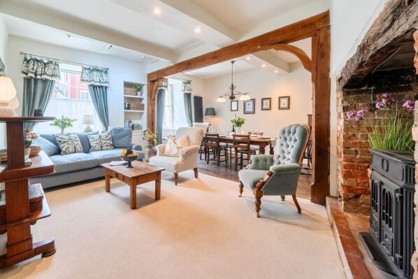 A cozy living room with a sofa, armchairs, a dining table, and a fireplace.
