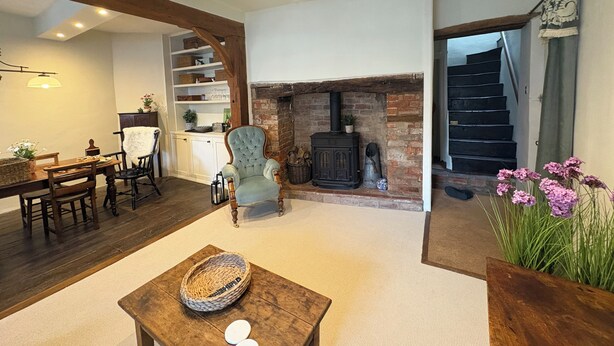 Amplia sala de estar con chimenea, muebles de madera y una escalera que sube a otro nivel.