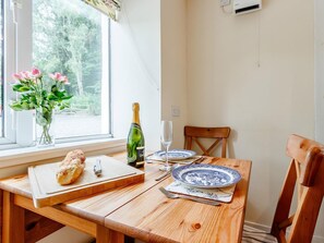 A dining table with a bottle of champagne, two glasses, a plate, and a bread roll. - 1 Bed in Blairgowrie (oc-ca361) (Blacklunans)