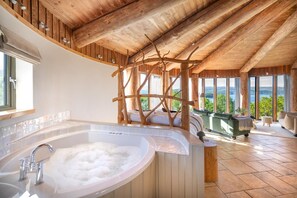 A spa area with a large bathtub, wooden ceiling beams, and a view of the outdoors.