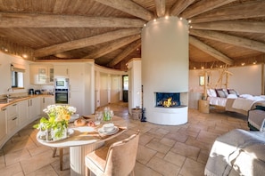 A spacious living area with a fireplace, a kitchen with modern appliances, and a dining area with a table set for two.