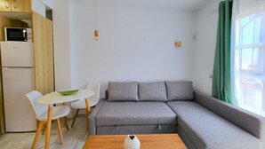 A modern living space with a grey sectional sofa, a small round table, and two white chairs. - Sol Suites Penthouse Plus Apartment (Fuengirola)
