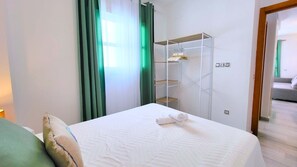 Ein Hotelzimmer mit einem Bett, einem Kleiderschrank und Blick auf ein weiteres Zimmer.