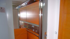 An elevator with orange walls and a metallic finish, featuring a control panel with buttons and a display. - Sol Suites Penthouse Plus Apartment (Fuengirola)
