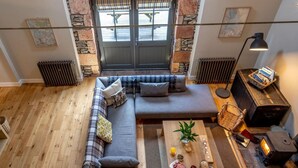 Ein gemütliches Wohnzimmer mit Steinwand, großem Fenster, einer Couch, einem Couchtisch und einem Kamin.