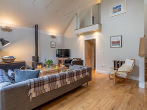 Ein modernes Wohnzimmer mit einer Couch, einem Sessel, einem Fernseher und einem Kamin.