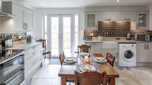 A modern kitchen with a dining area, featuring a built-in oven, microwave, and washing machine. - 2 Bed in Dalmally (oc-ca379) (Dalmally)