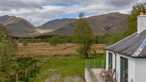 A house with a patio, a view of mountains, and a fenced field. - 2 Bed in Dalmally (oc-ca379) (Dalmally)