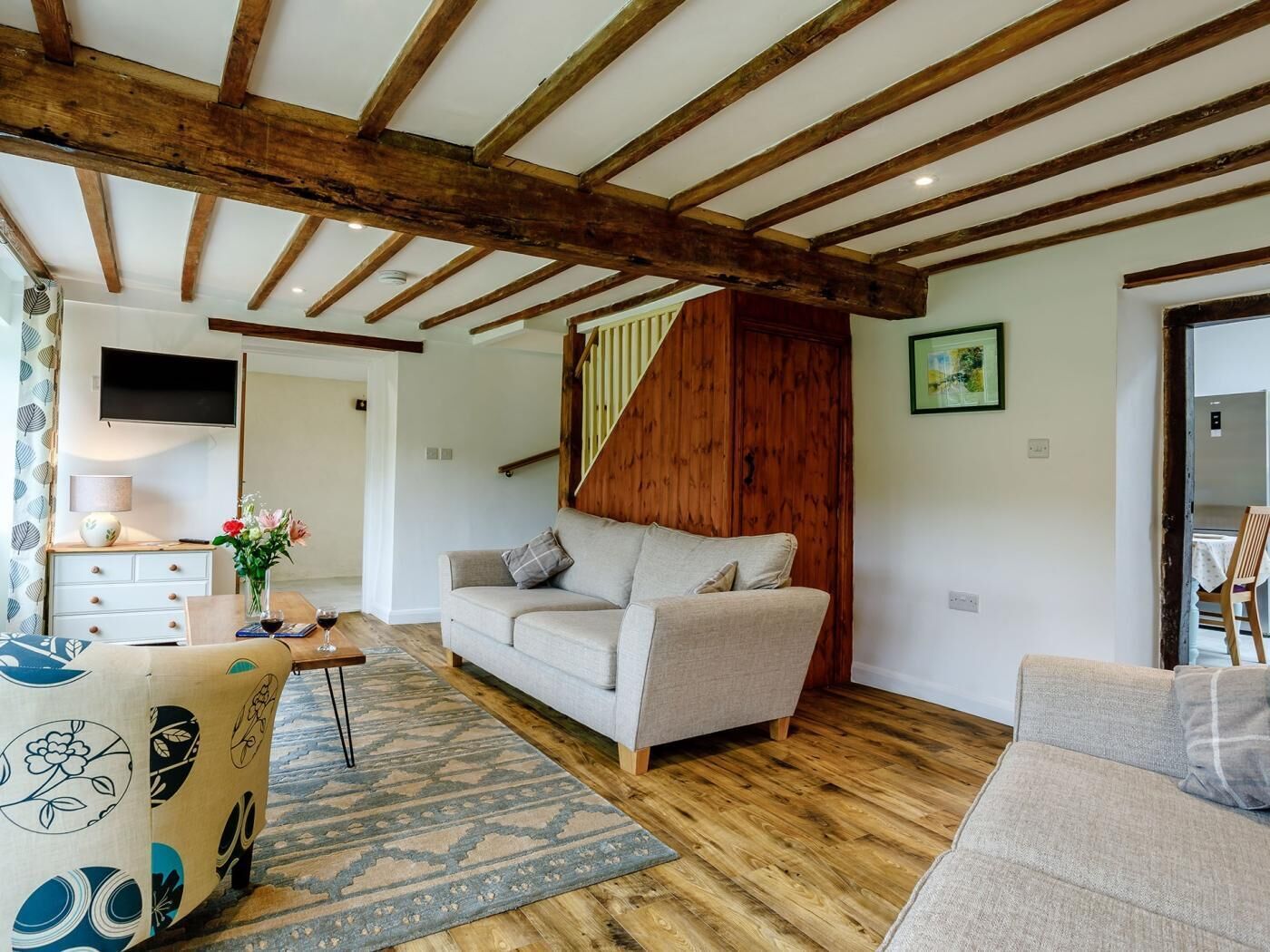 A living room with a sofa, a coffee table, a TV, and a staircase.