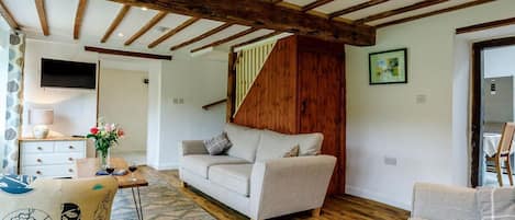Una sala de estar con un sofá, una mesa de centro, un televisor y una escalera.
