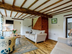 A living room with a sofa, a coffee table, a TV, and a staircase. - 3 Bed in Bridport (oc-76820) (West Milton)