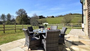 Une terrasse dotée de meubles en osier et d’une table dressée pour quatre personnes, le tout entouré d’un sol en pierre.