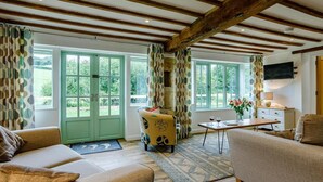 Une pièce avec des poutres en bois, un canapé, une chaise, une table et un téléviseur.