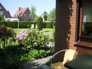 Ein Garten mit Blumen und einem Stuhl vor einem Gebäude.