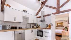 Uma cozinha moderna com armários brancos, eletrodomésticos de aço inoxidável e vigas de madeira aparente.