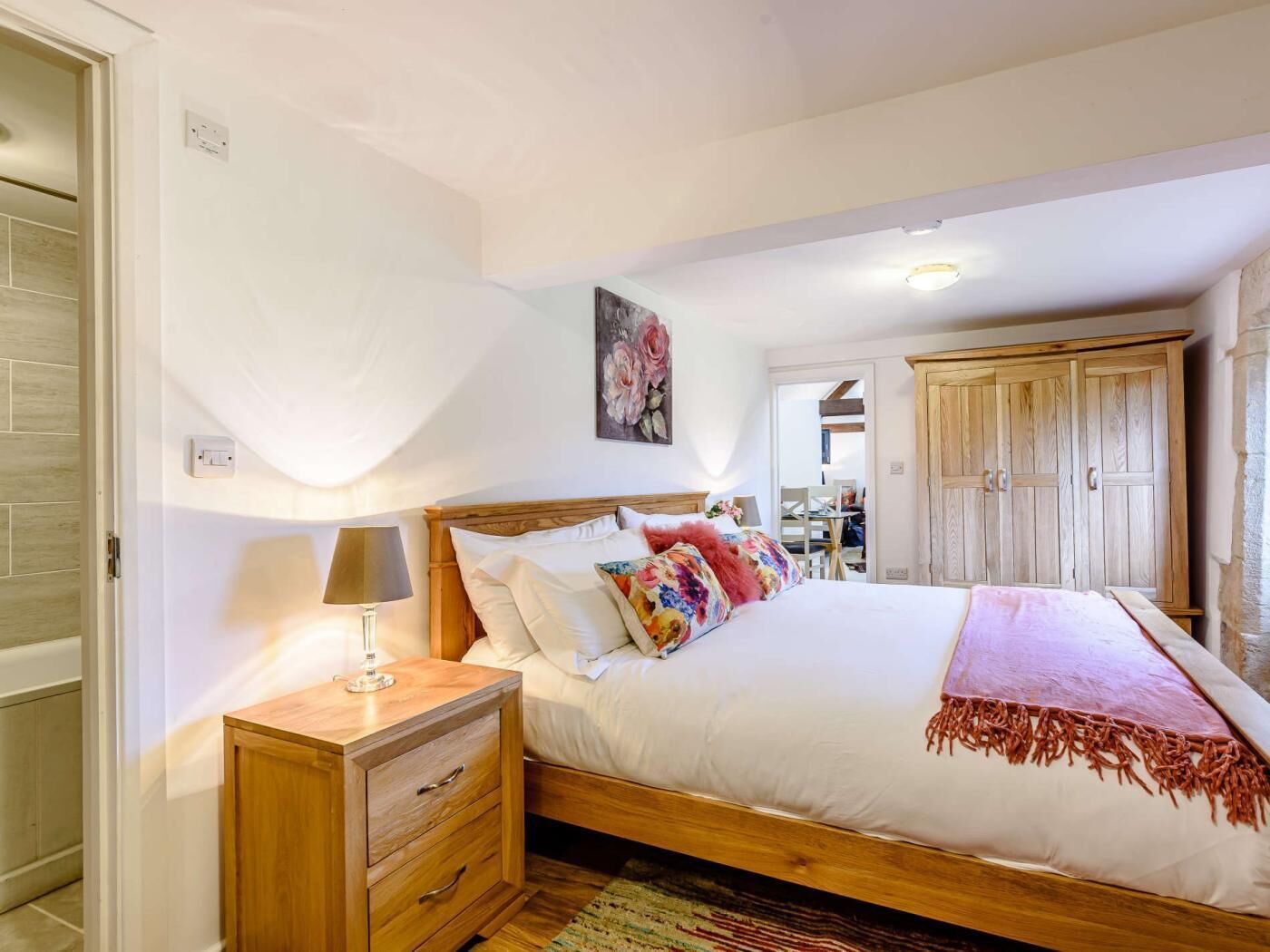 Een slaapkamer met een houten bed, nachtkastjes, een lamp, een schilderij en een kledingkast.