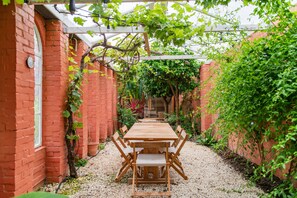 A brick building with a wooden table and chairs in a garden area. - The Manor, Deal, Kent (Deal)