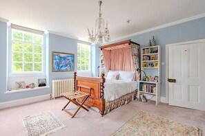 A bedroom with a four-poster bed, a chandelier, a bookshelf, and a large window. - The Manor, Deal, Kent (Deal)