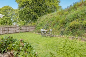 A backyard with a wooden fence, a grassy lawn, and a table with chairs.