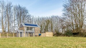 Ein modernes Haus mit Solardach, umzäuntem Garten und einer Steinmauer.