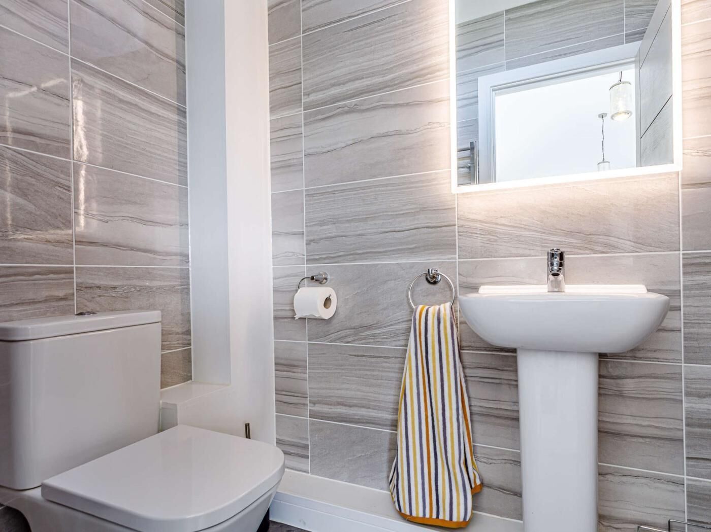 A bathroom with a toilet, a sink, and a towel rack.