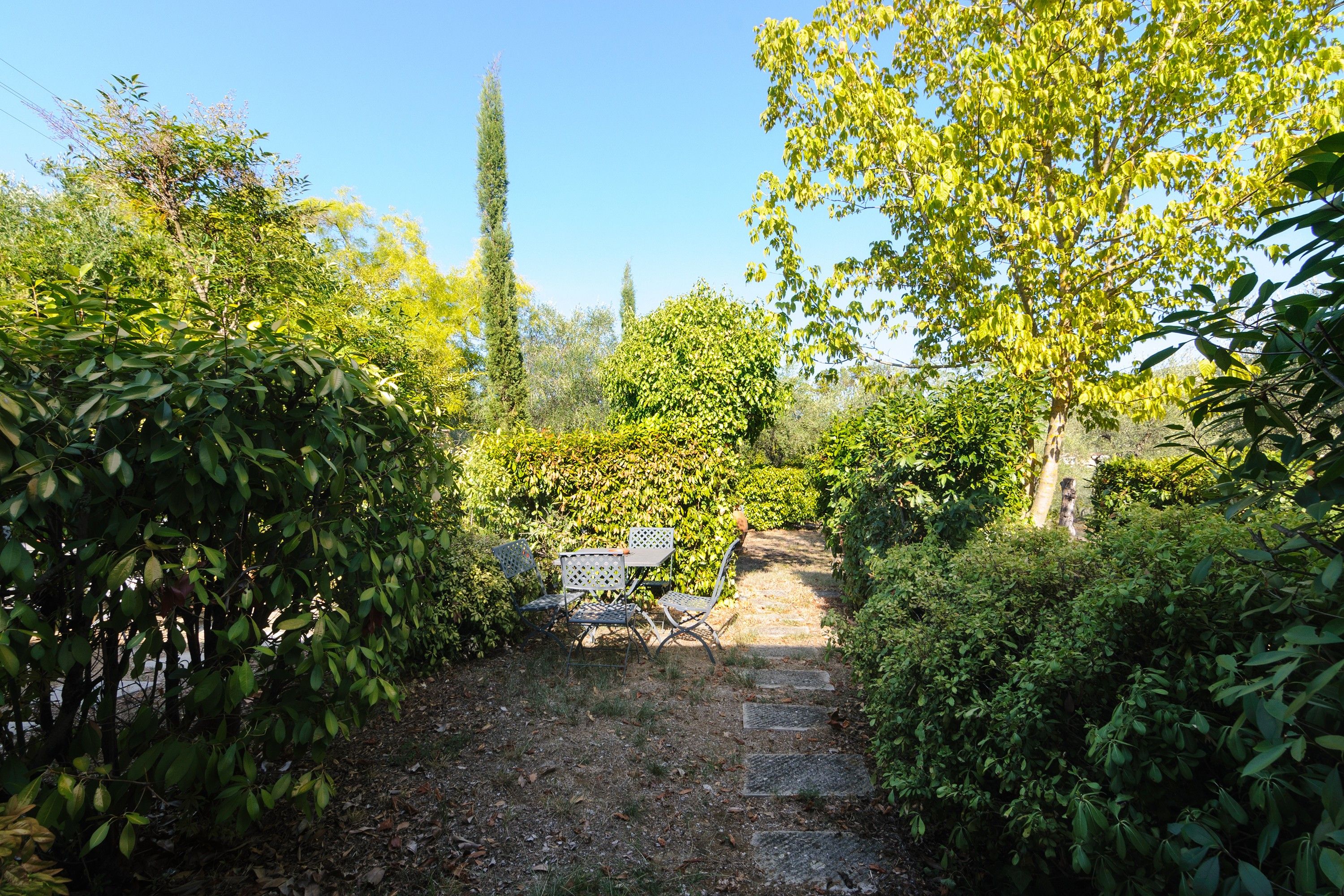 Un jardín con un camino de piedra que lleva a una mesa y sillas.