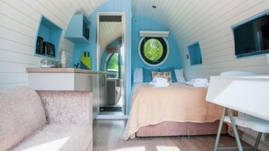 A compact bedroom with a bed, a small desk, a chair, and a window.